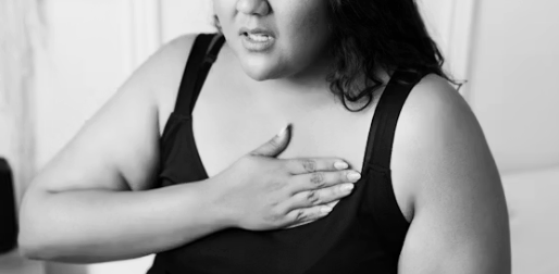 A woman wearing a sleeveless top holding her chest in apparent discomfort or pain.