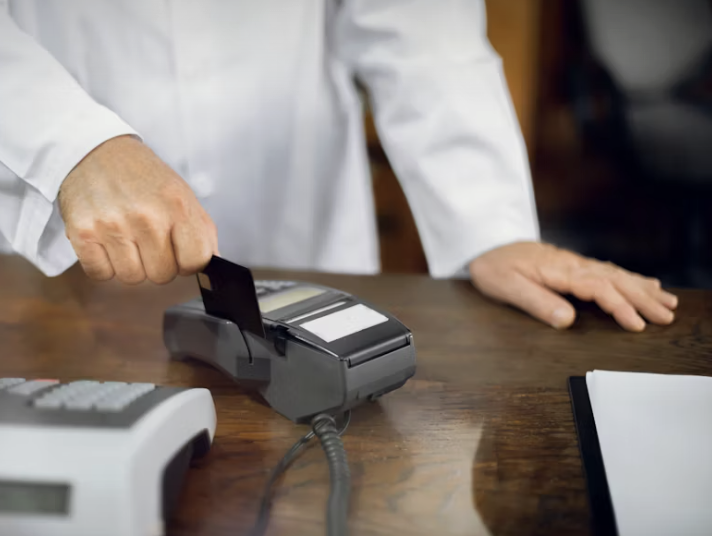 Person in a white shirt using a credit card on a point-of-sale terminal.