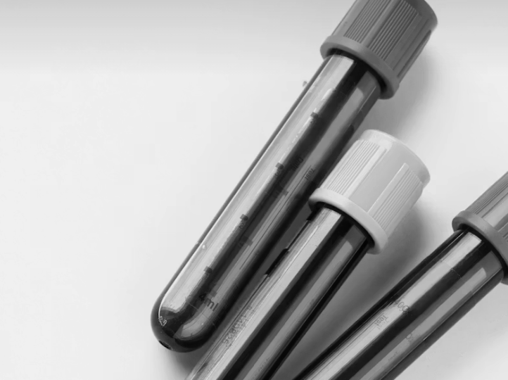 Three blood collection tubes with gray and white caps on a white surface.