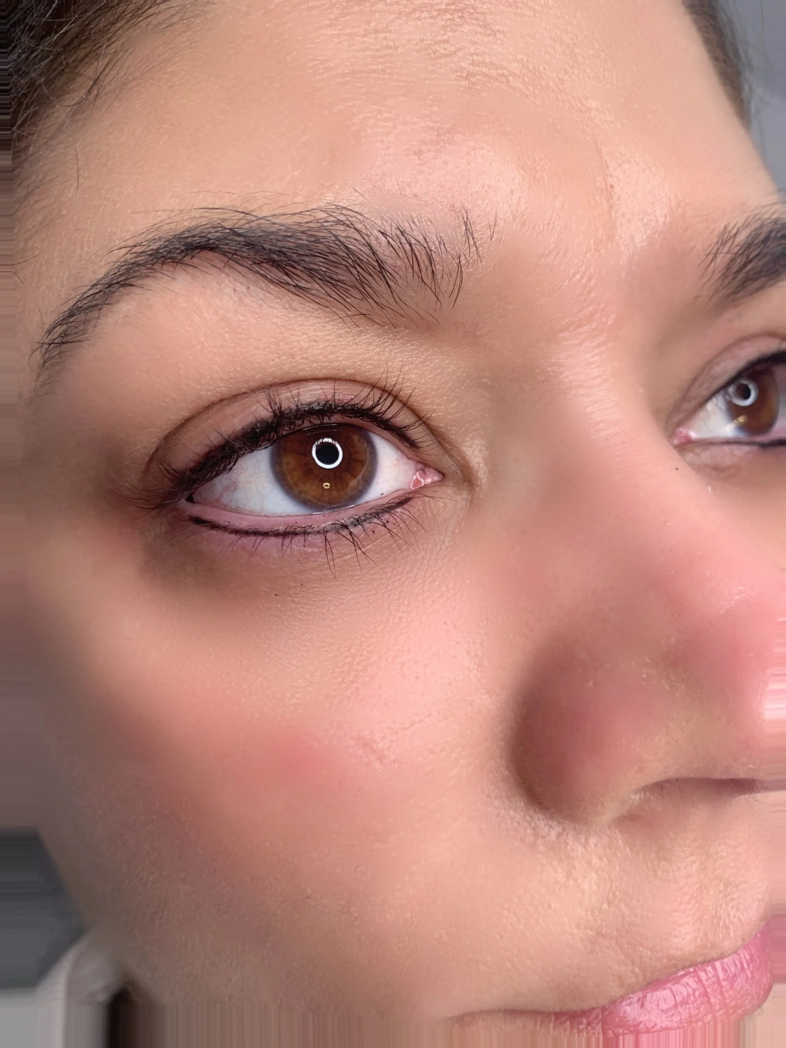 Close-up of a woman's face showing her right eye, eyebrow, and part of her lips, with natural makeup and smooth skin.