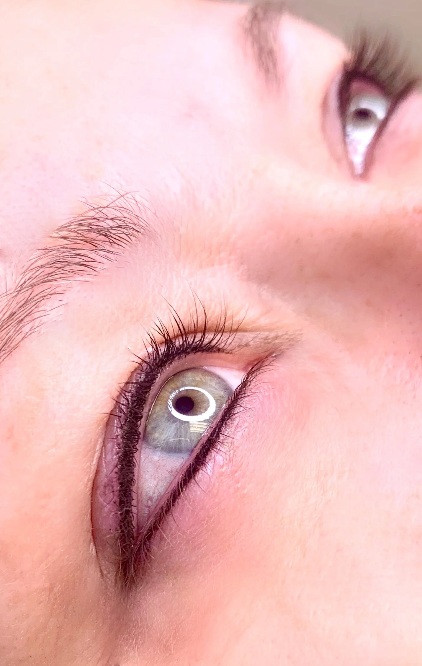 Close-up of a person's eye with visible eyelashes and eyebrow, skin details, and lighting reflections in the eye.