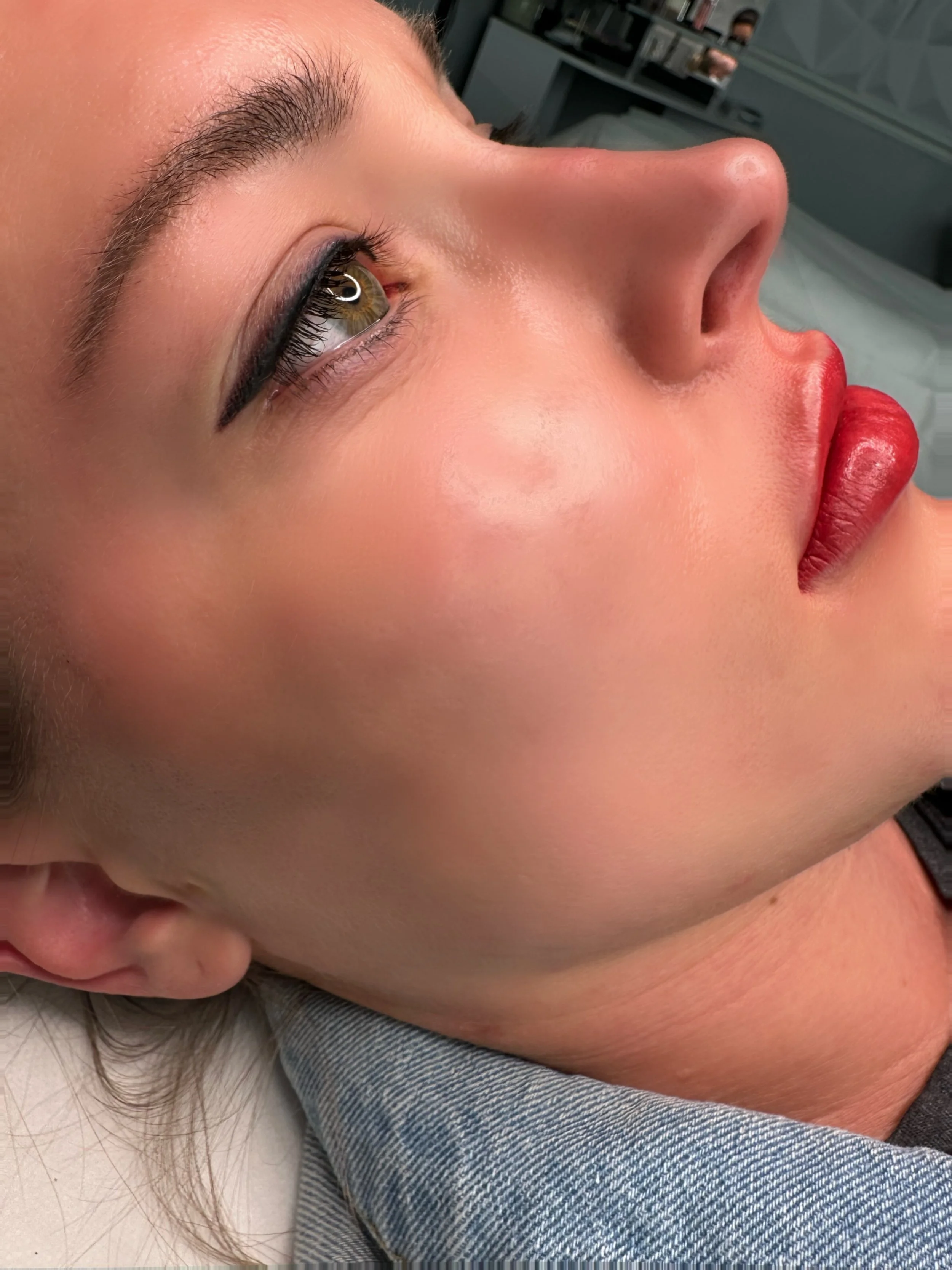 Close-up of a woman's face showing her eye, nose, and lips, with makeup on her eye and lips.