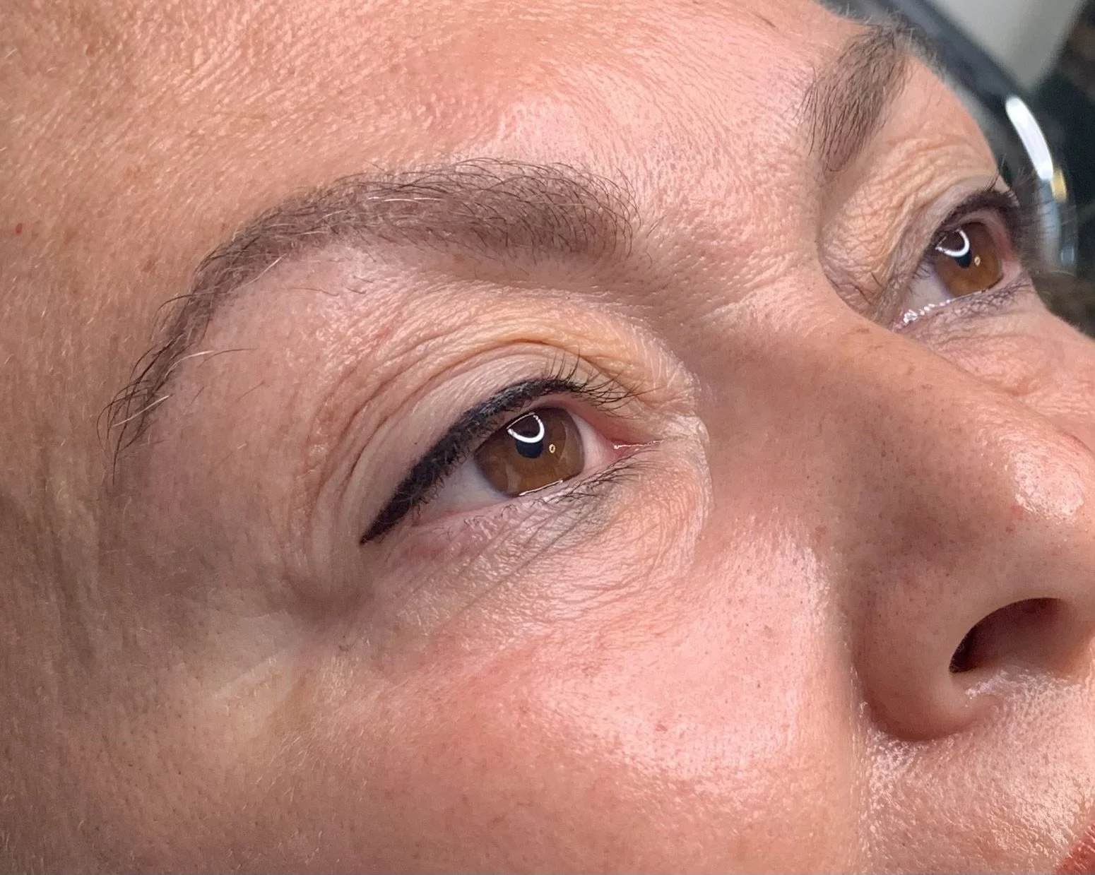 Close-up of a person's face focusing on the eyes and eyebrows, with natural skin texture and brown eyes.