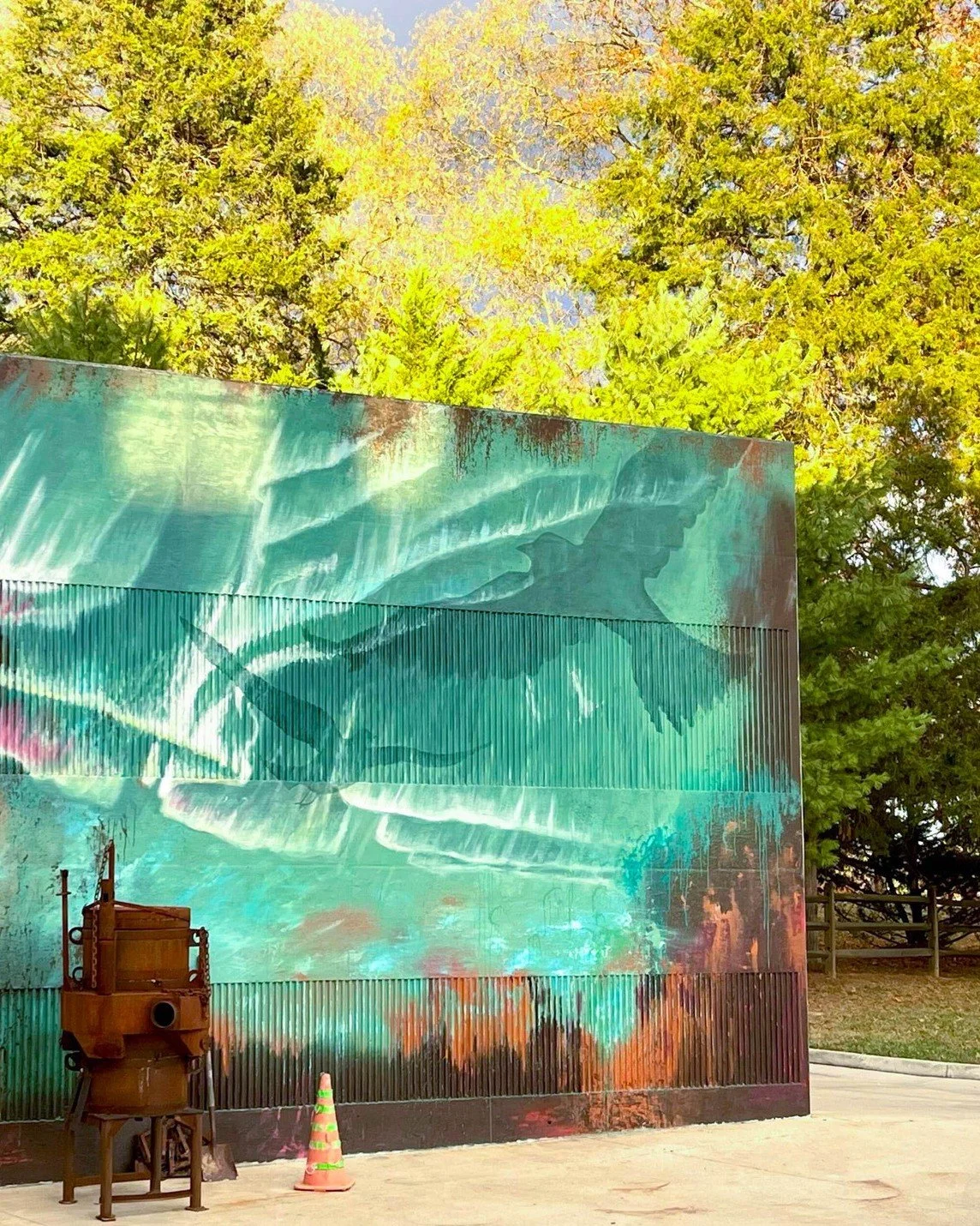 The finished mural in front of the tree line in the summer.