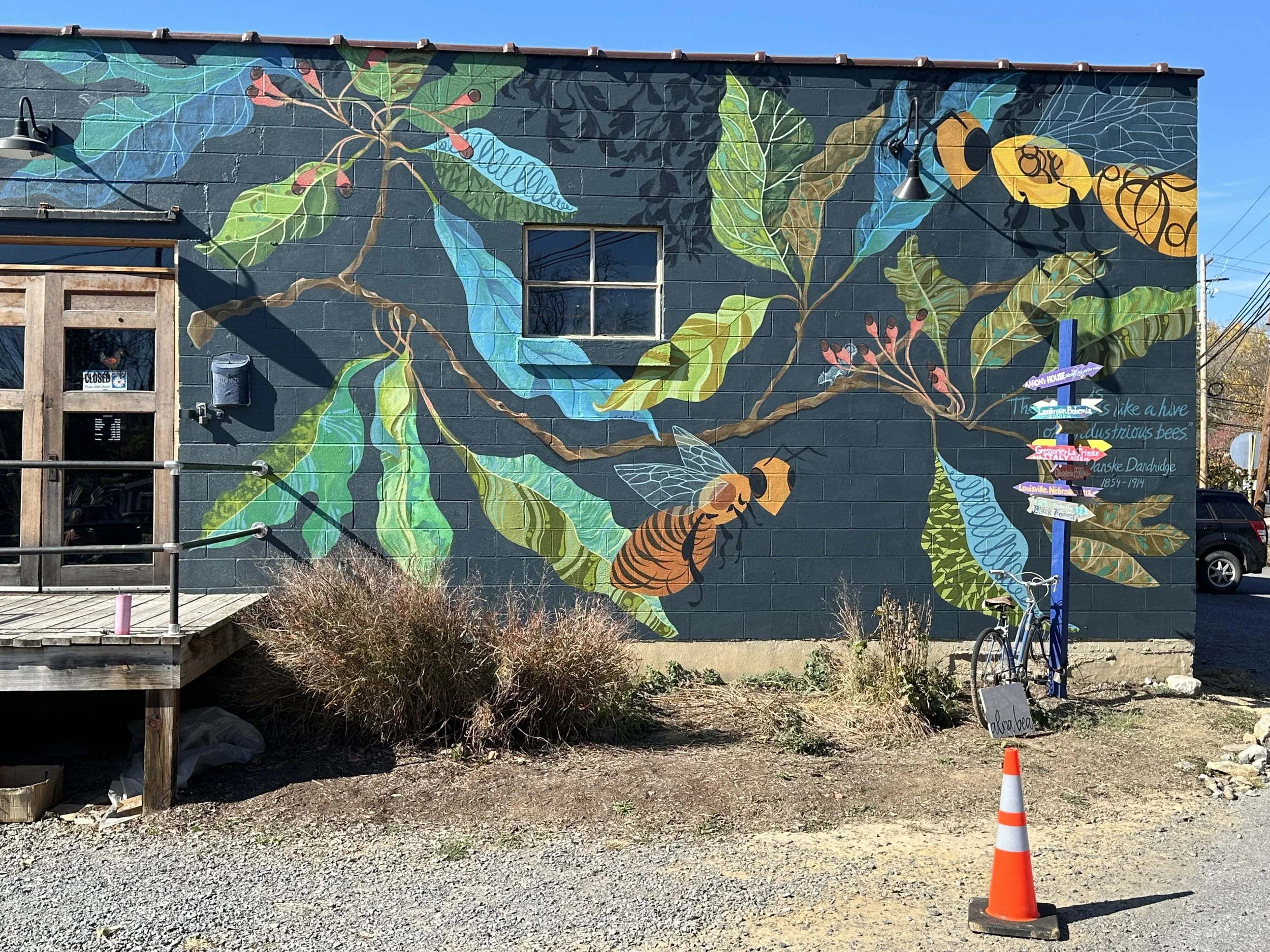 A close-up of the finished Gateway Mural during the day, featuring a quote by Danske Dandridge - "The town is like a hive of industrious bees." The dappled sunlight details can be seen best in the bright lighting.