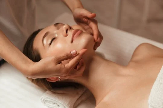 A woman receiving a facial massage in a spa setting