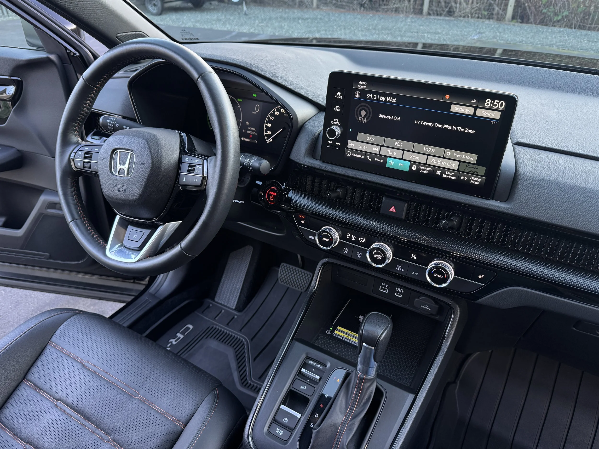 Clean interior of a Honda vehicle showing the steering wheel, dashboard, centre console, digital display, climate controls, and gear shift.