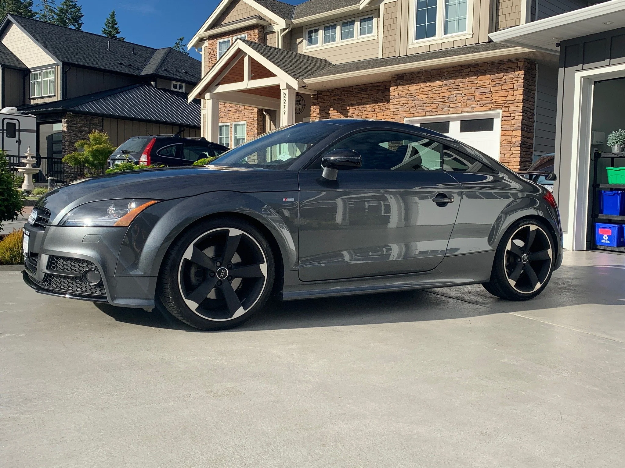 Gray Audi convertible detailed and parked in driveway in front of a residential house with brick and siding exterior.