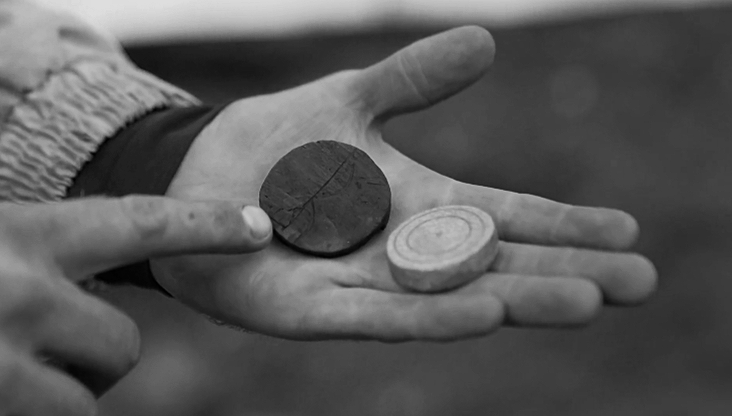 Pieza de juego medieval de hueso con inscripciones rúnicas Raido y Uruz, hallada en Tønsberg, Noruega. Detalle del desgaste y la talla del símbolo en ambas caras del objeto arqueológico.