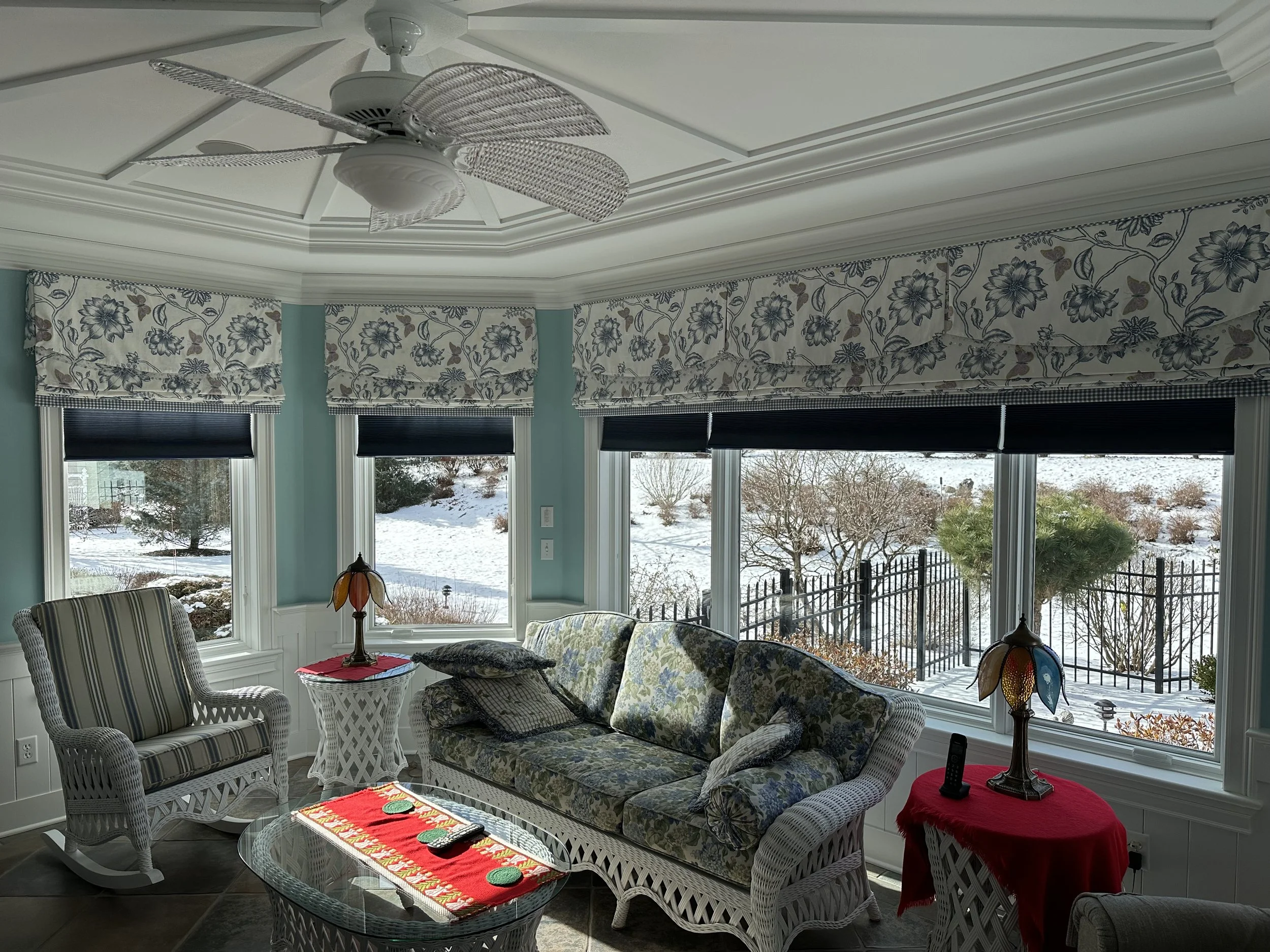 This beautiful sunroom is set off with royal blue motorized cellular shades tucked under faux Roman shades and scalloped valances.