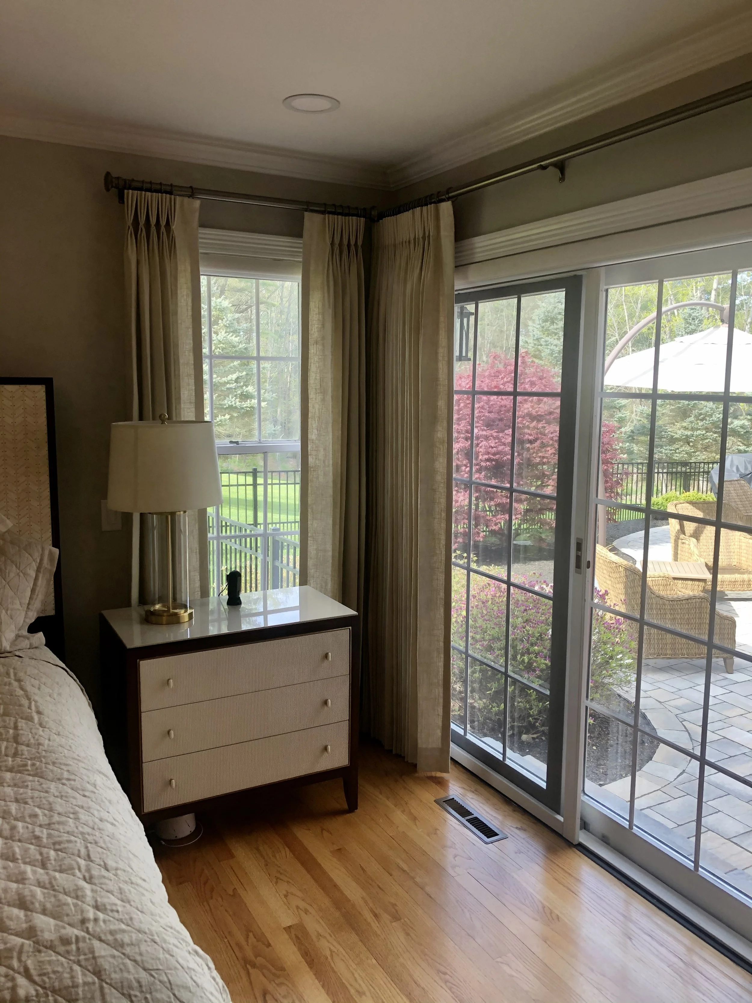 A cozy bedroom corner with room darkening custom draperies and beautiful decorative metal poles.