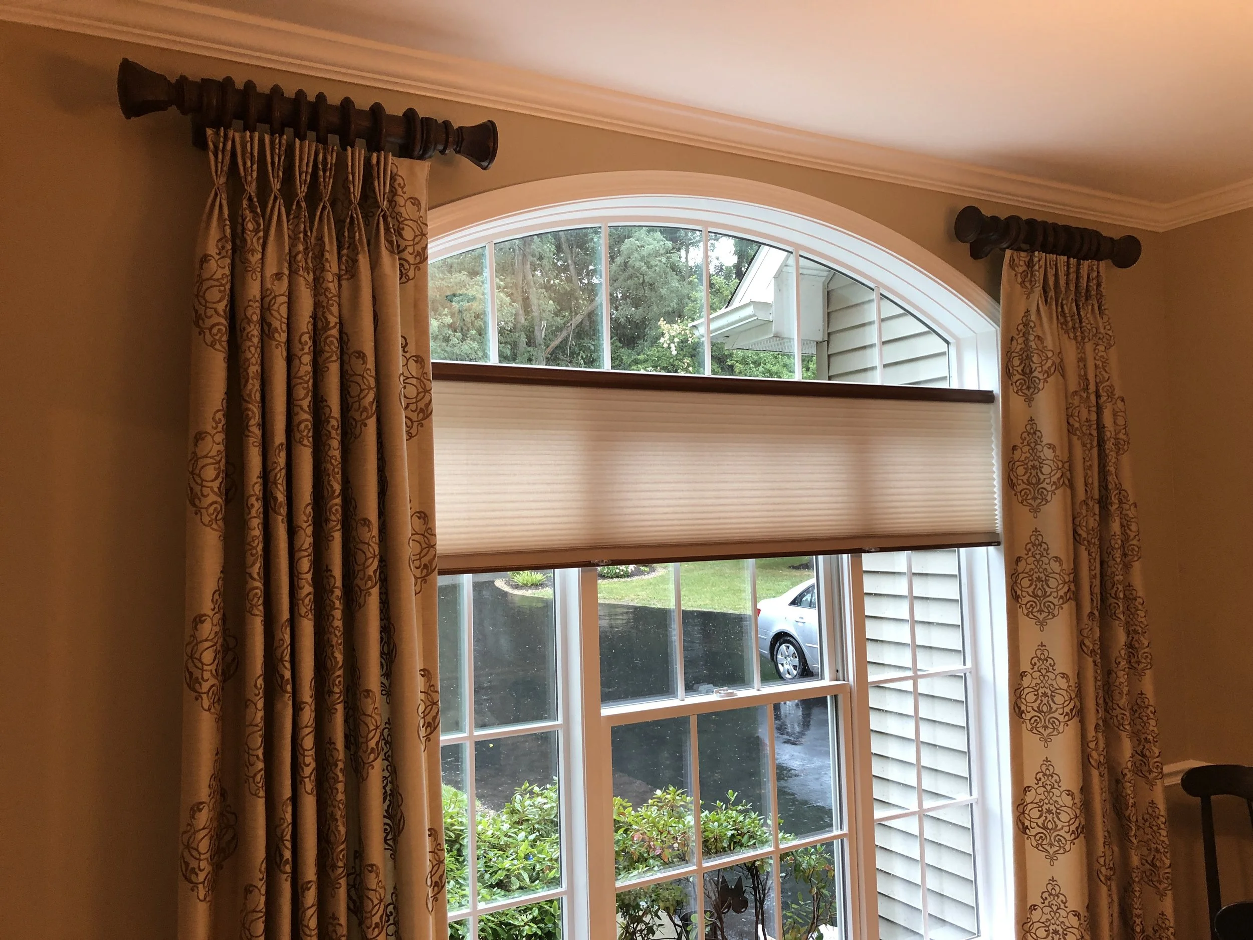 Stationary pinch pleated draperies on poles and cellular shades for privacy