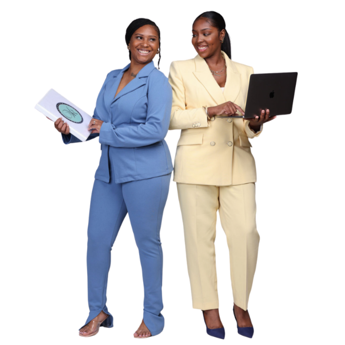 Two women in business suits, one in blue holding a notebook, the other in yellow using a laptop, standing together and smiling.