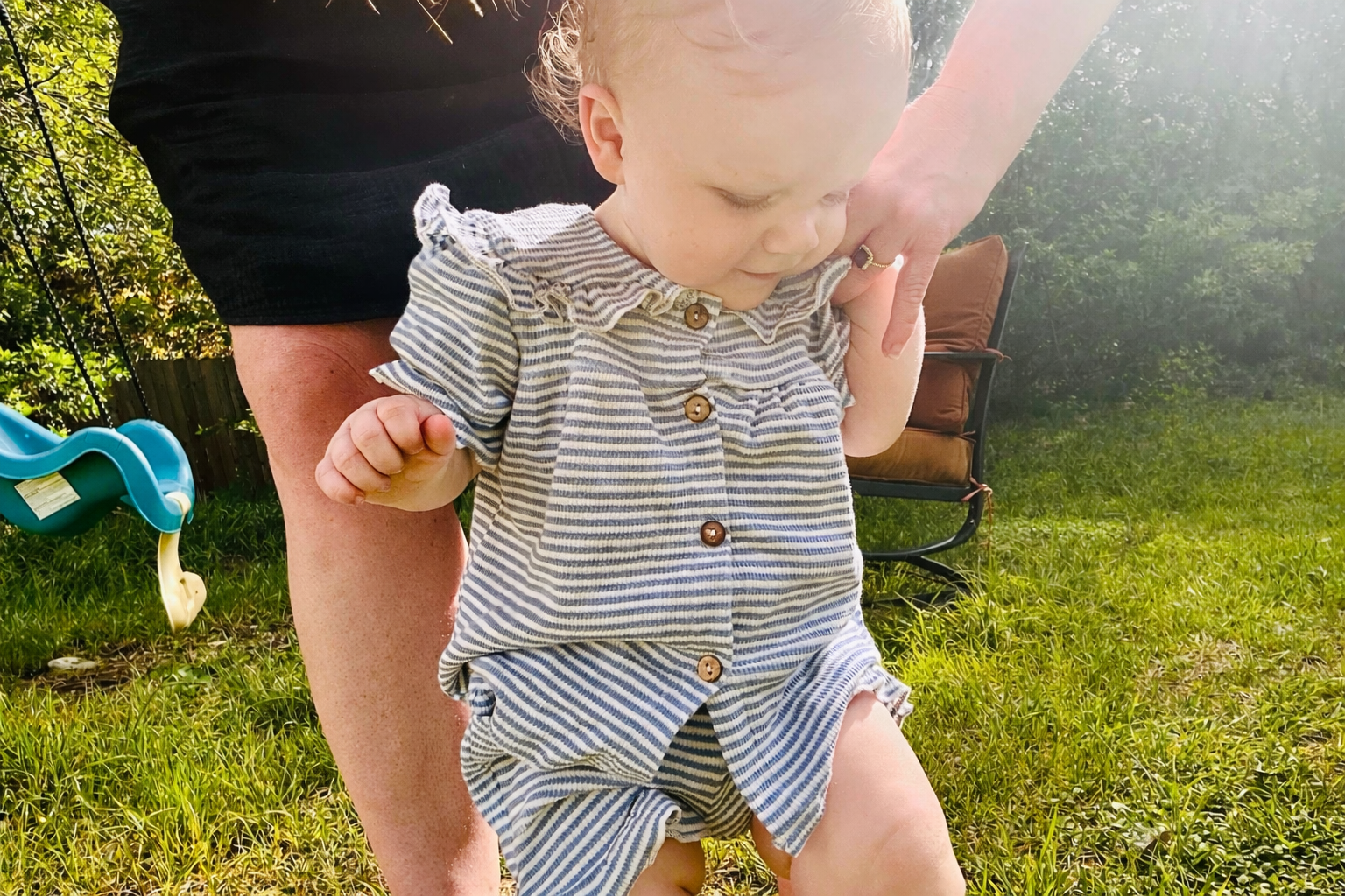 A young toddler girl in a striped dress walking outside with her mother, Abigail, illustrating a journey of finding peace and joy in everyday motherhood.