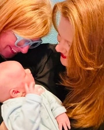 Three generations together — grandmother, mother, and baby sharing a quiet family moment during early motherhood.