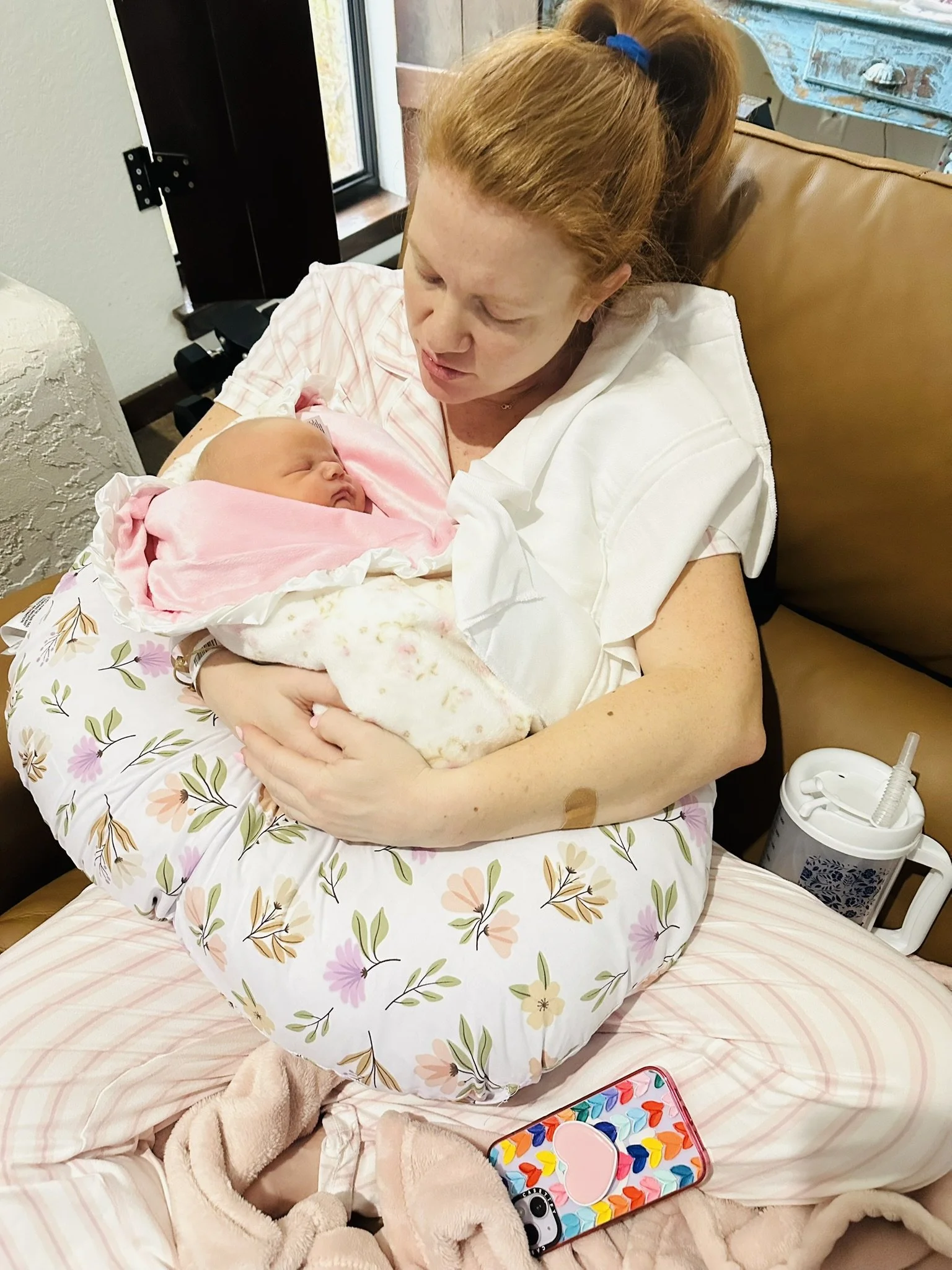 A postpartum mom recovering and holding her sleeping newborn