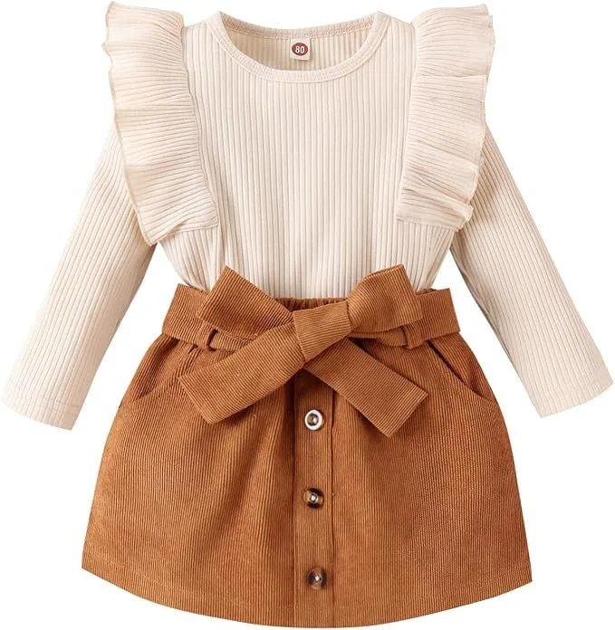 Toddler girl outfit: skirt set with a cream ribbed ruffle shoulder top and brown burnt orange corduroy button-front skirt with a bow.