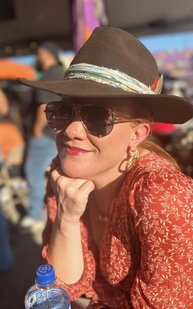 Woman in cowboy hat and sunglasses smiling outdoors during TX OU weekend in Texas.