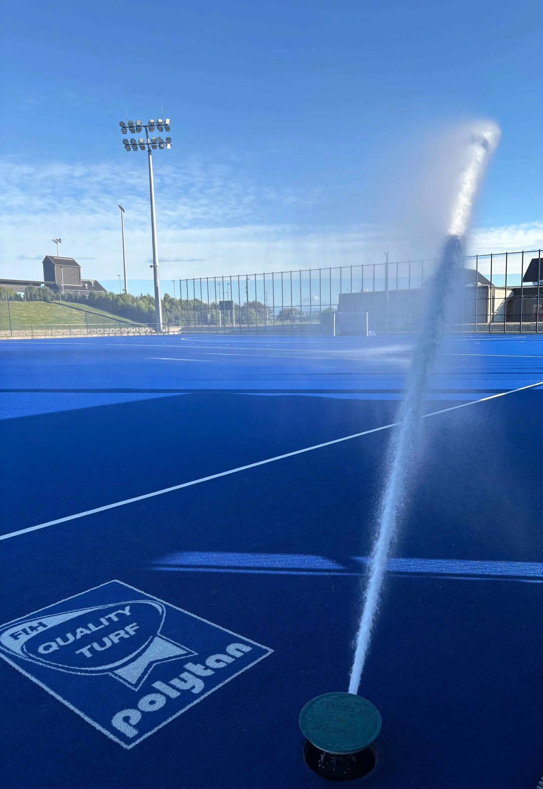 Sports court irrigation under a clear sky.
