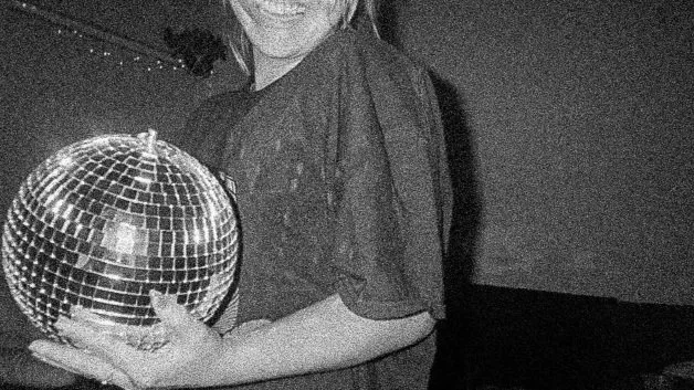 Person holding a disco ball in a dimly lit interior.