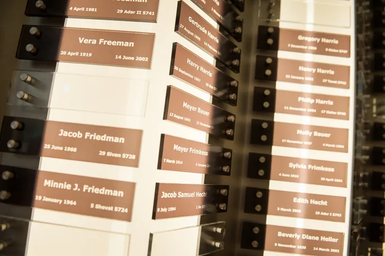 Memorial plaques on a wall listing names and dates of deceased individuals.