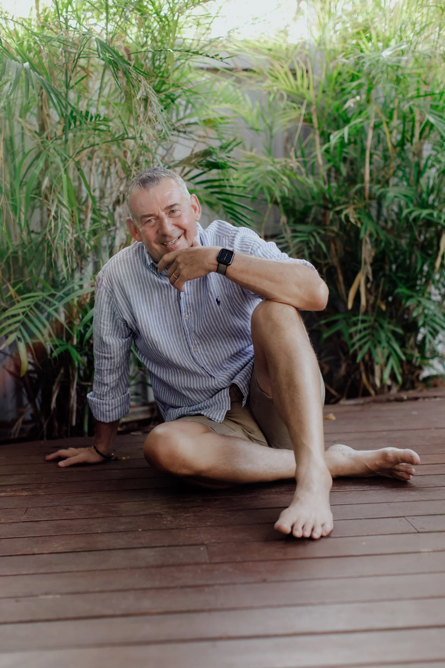 wedding celebrant sitting on decking at home infront of palms