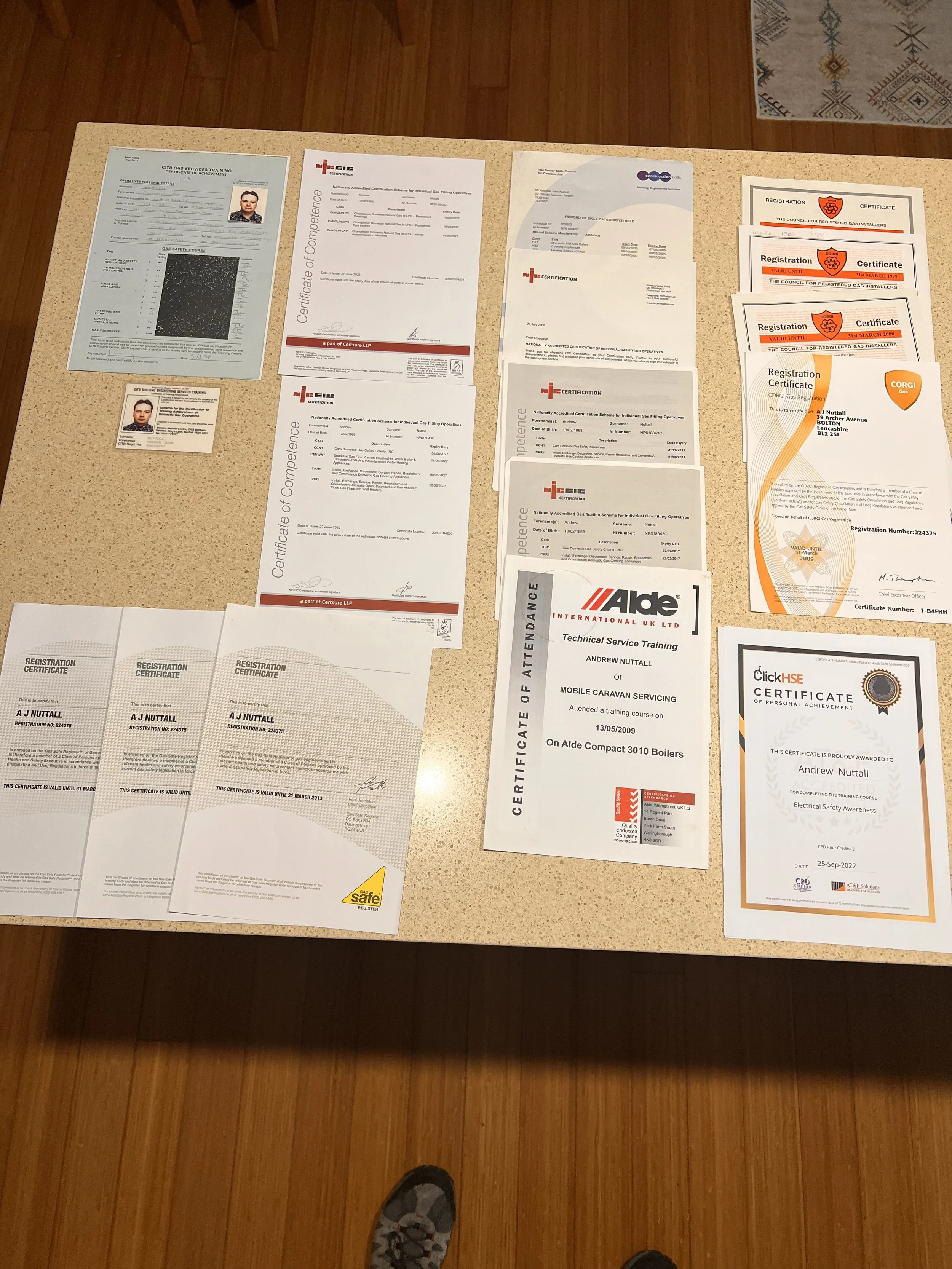 Various certificates and identification cards laid out on a table, with a wooden floor visible below.
