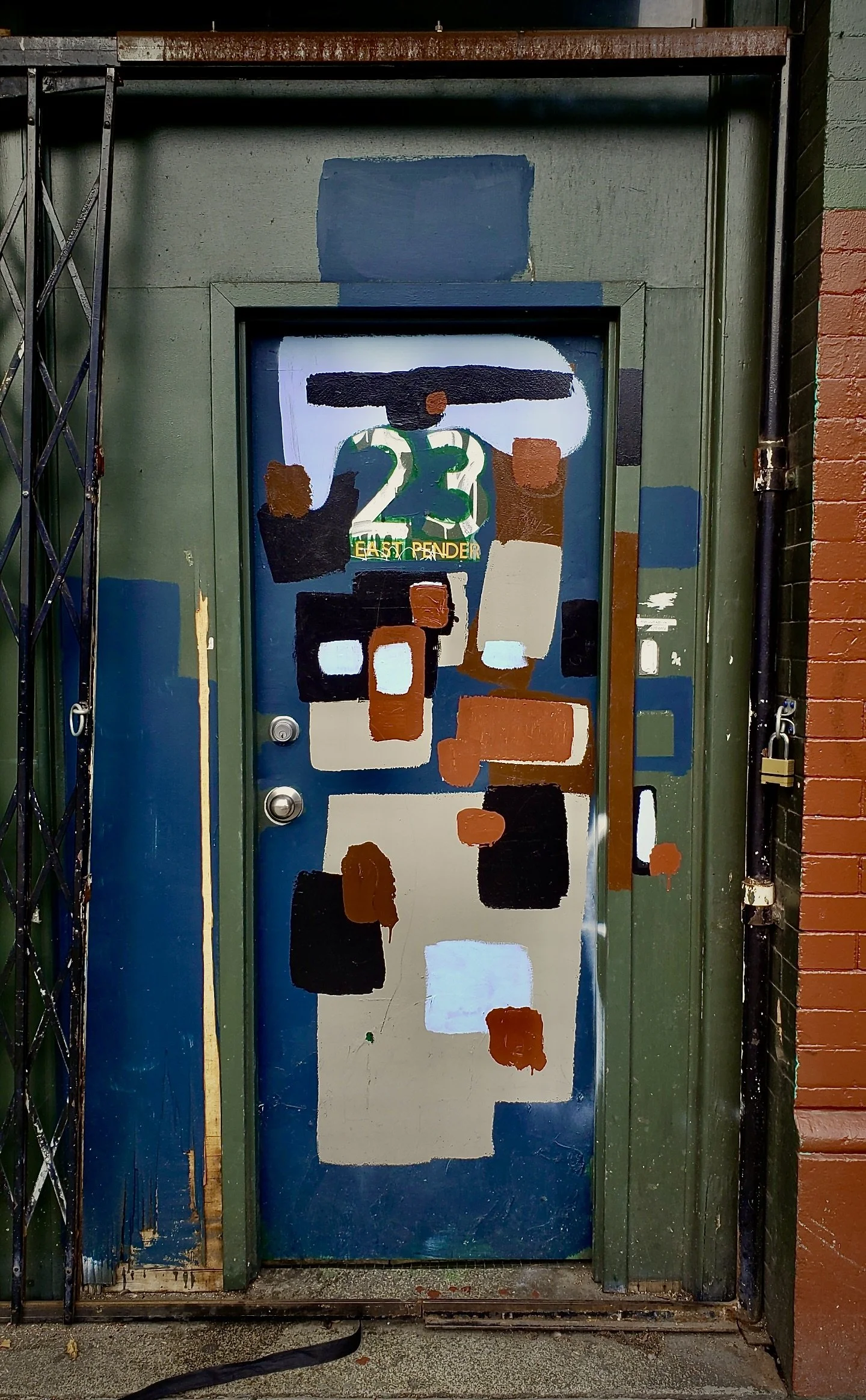 A street door that appears to be abstract mural art with geometric shapes and colours, including a large number 23 in green.