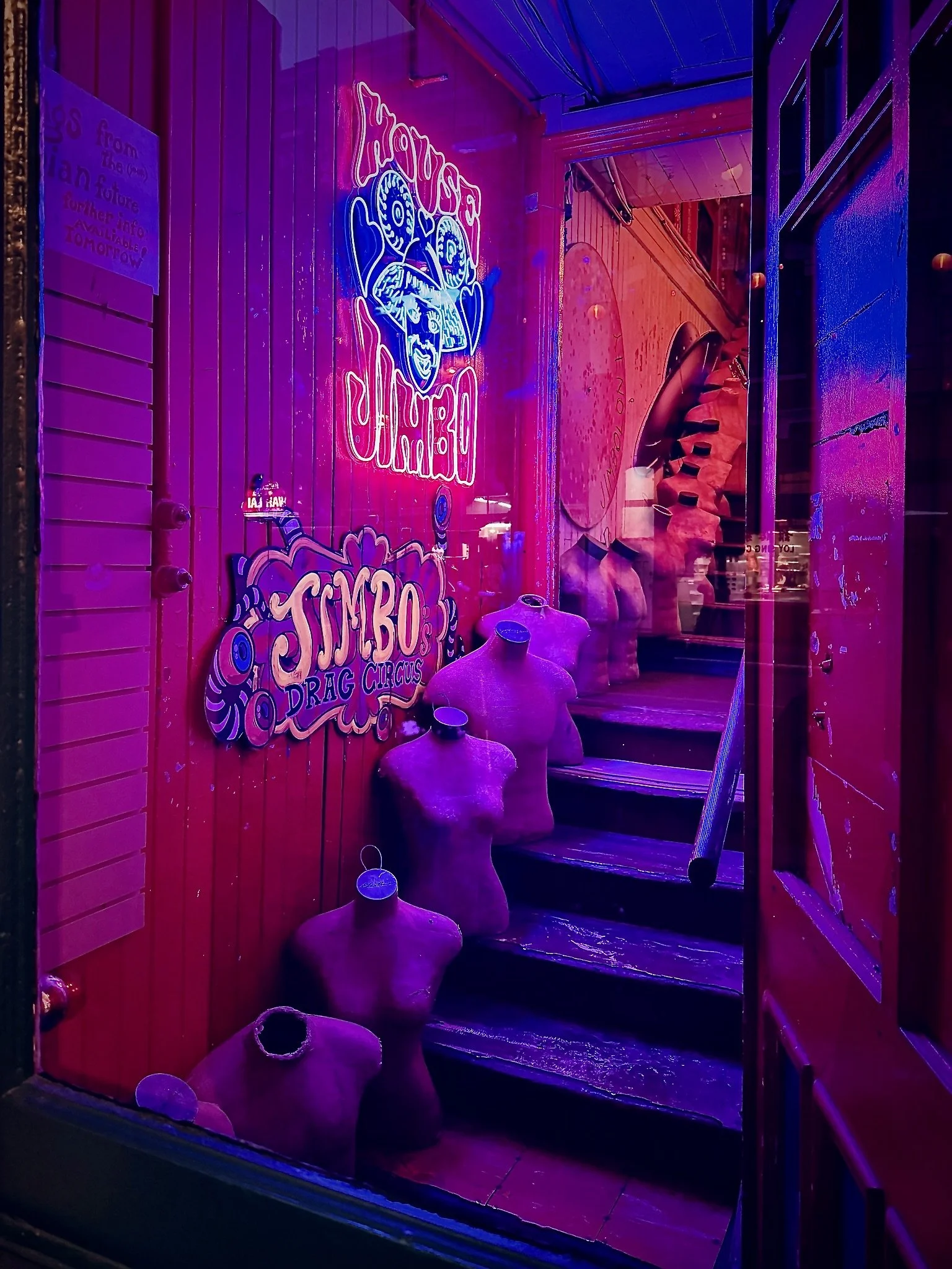 Neon-lit entrance with a staircase, mannequin torsos on the steps, and signs for a design studio in Victoria called 'House of Jimbo'.
