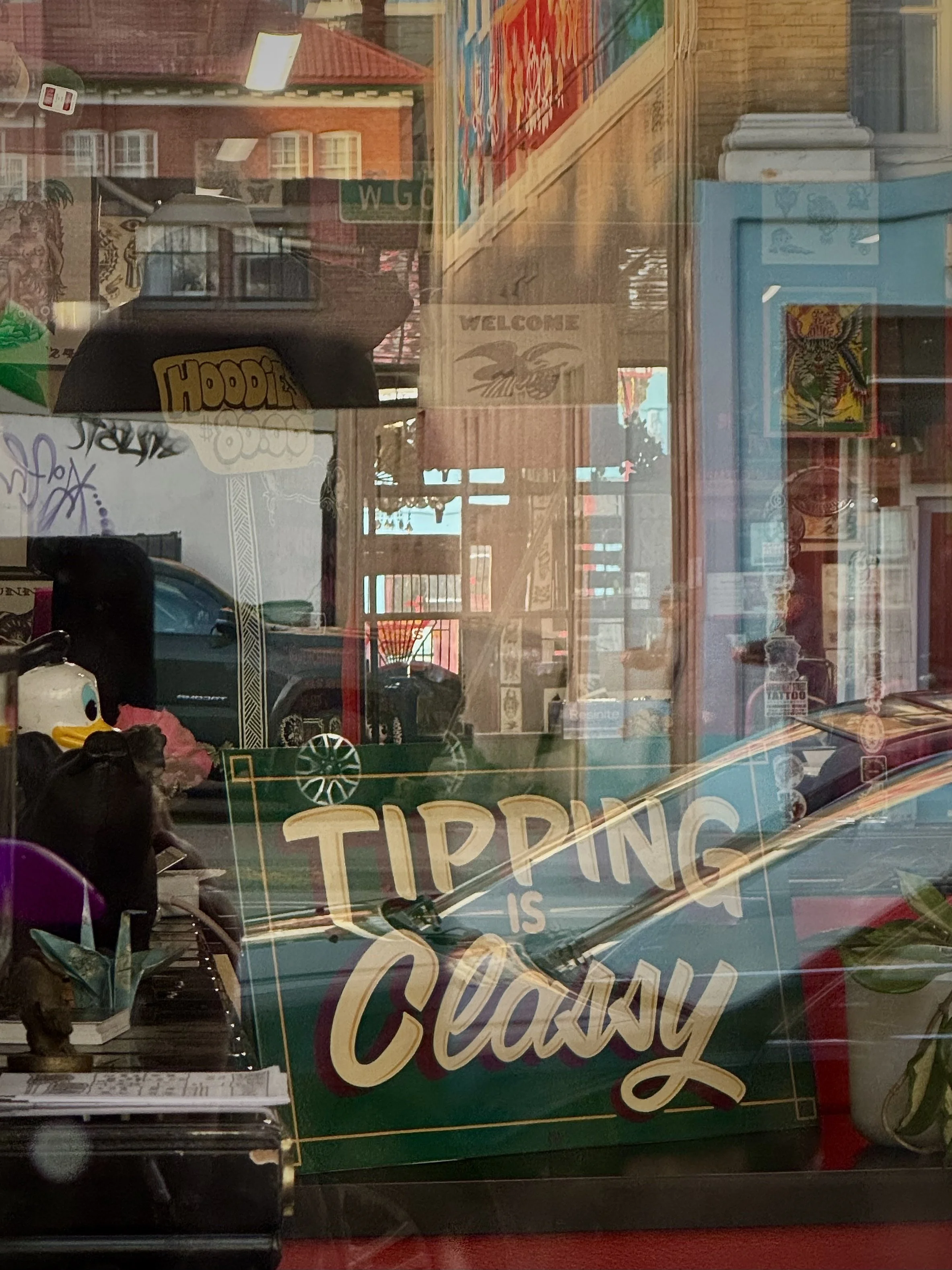 Reflection of storefront window with a sign that reads "TIPPING IS CLASSY".