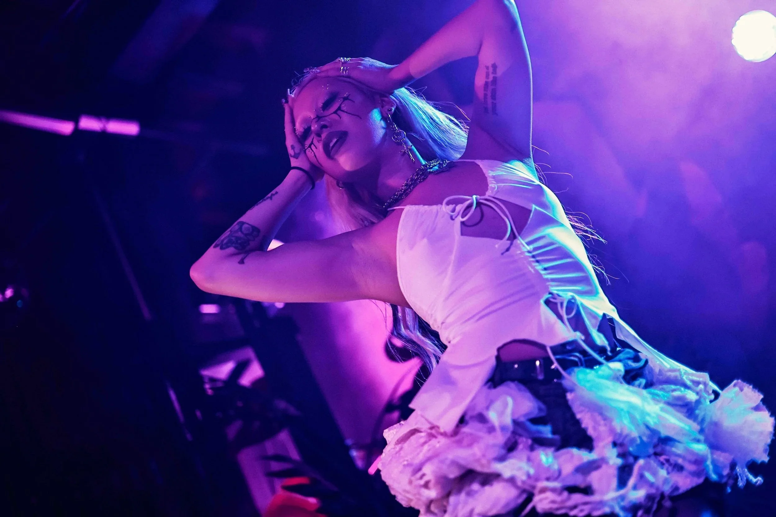 Lahbra, with blonde hair, tattoos, and jewelry dancing at Ricecake: Remix, 2025.