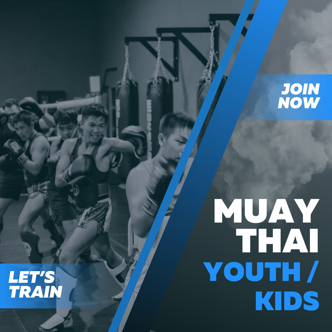 Young boys participating in a Muay Thai training session with boxing gloves in a gym with punching bags in the background.