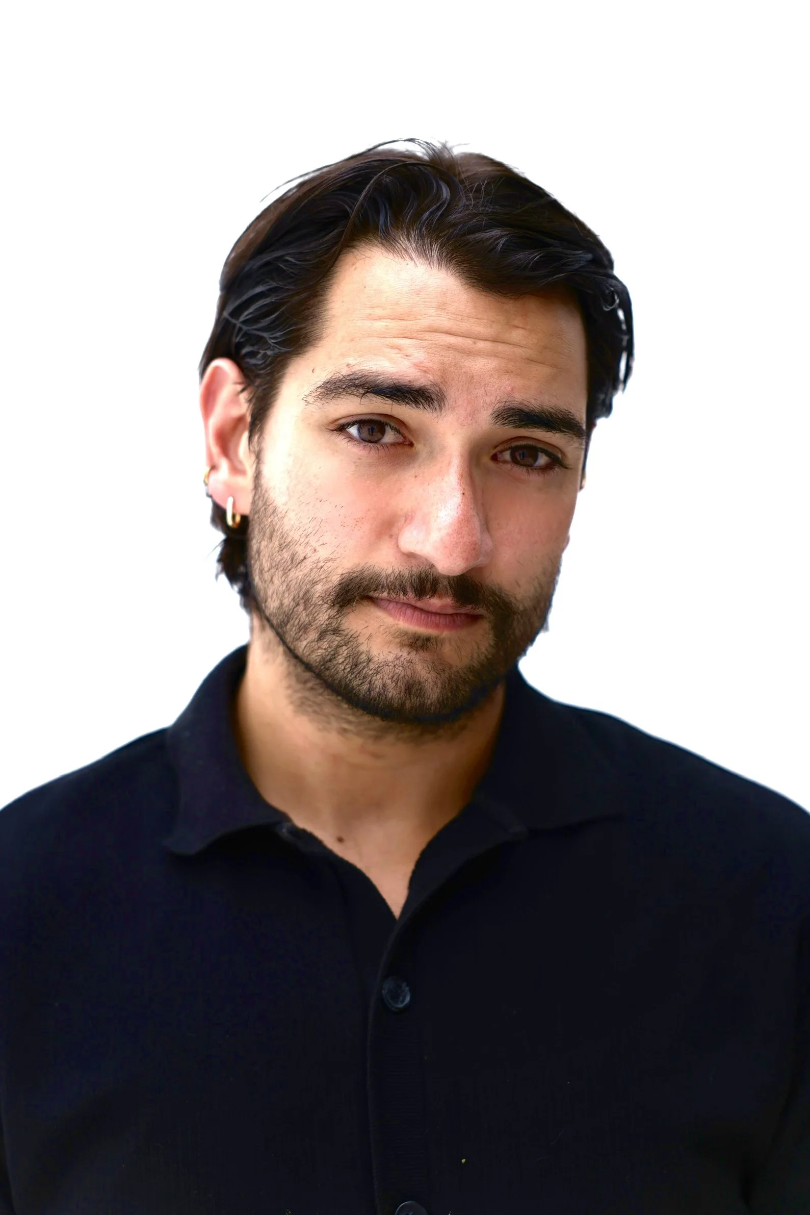 young person of color with concerned but kind look in black button up against white backdrop