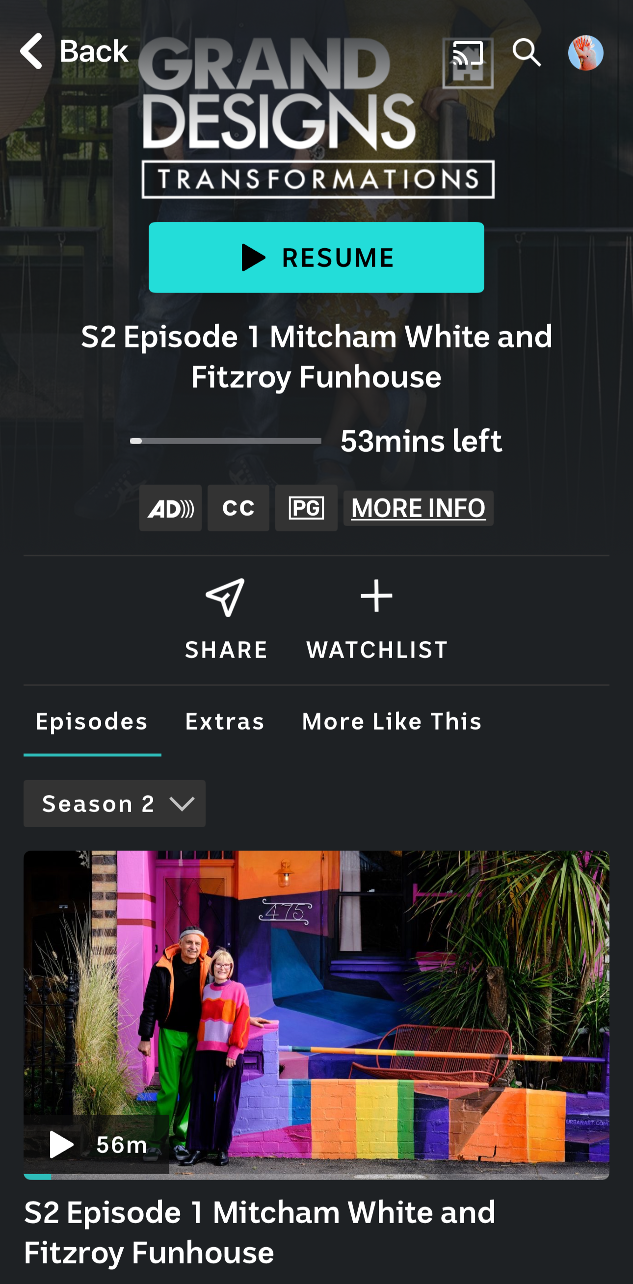 A colorful mural featuring vibrant pink, purple, blue, green, yellow, and orange geometric shapes, with two people standing in front of it, one wearing a black jacket with an orange hood and green pants, and the other wearing a multicolored sweater and dark pants.