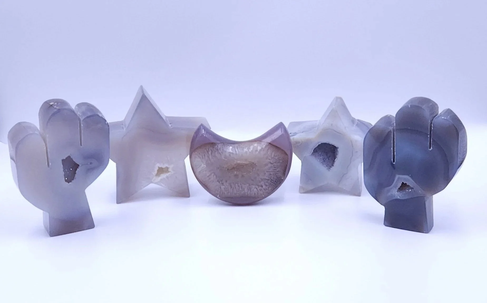 Five agate stones with druzy, carved into various shapes, displayed on a white background