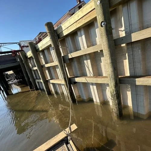 Flooded area with wooden and concrete dock structures and water covering the ground.