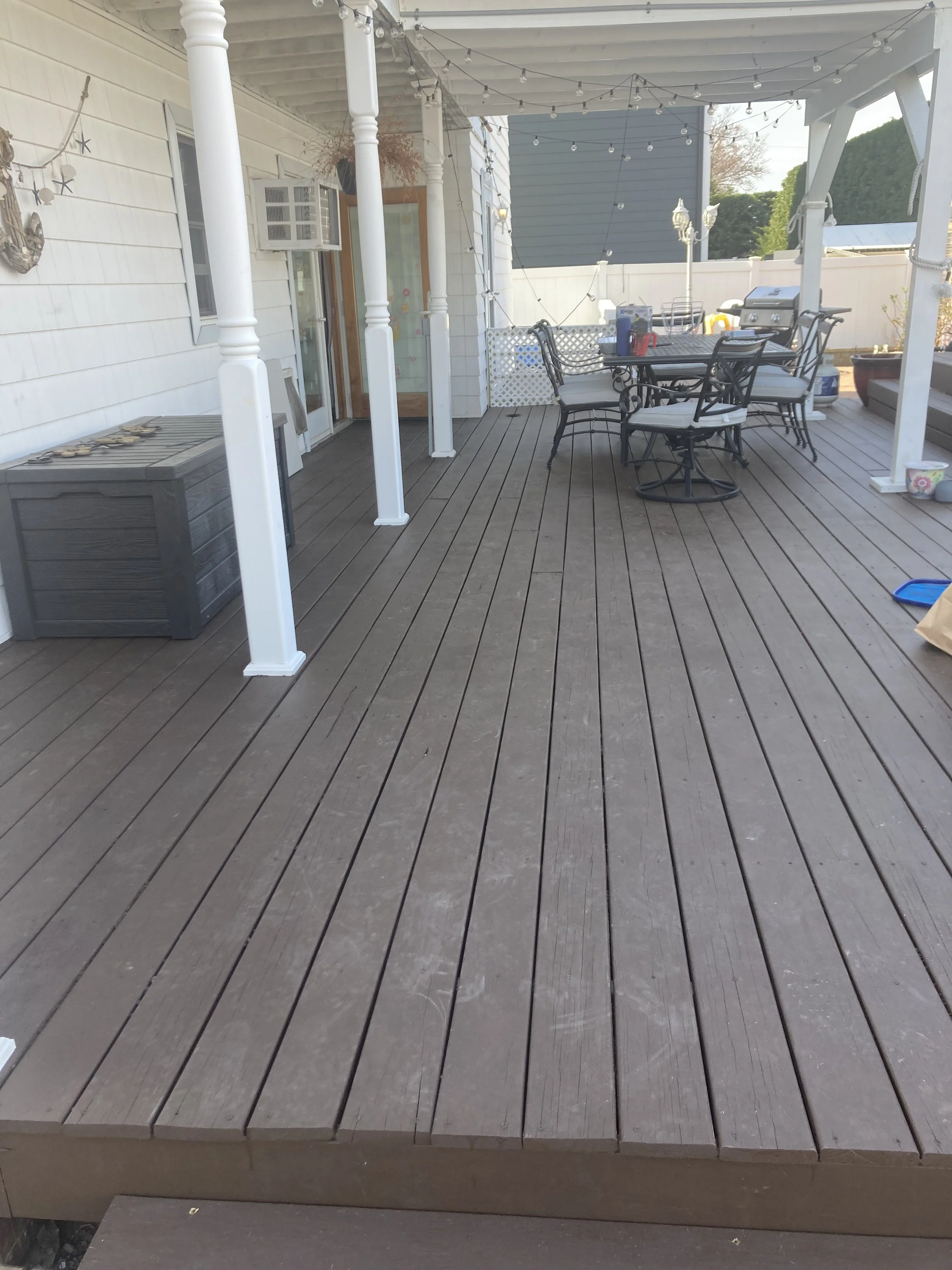 Backyard deck with outdoor furniture, string lights, and surrounding decorations.