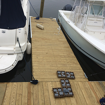 View of a wooden dock with boats on both sides and a set of carved stones with the words 'HELLO' on the dock.