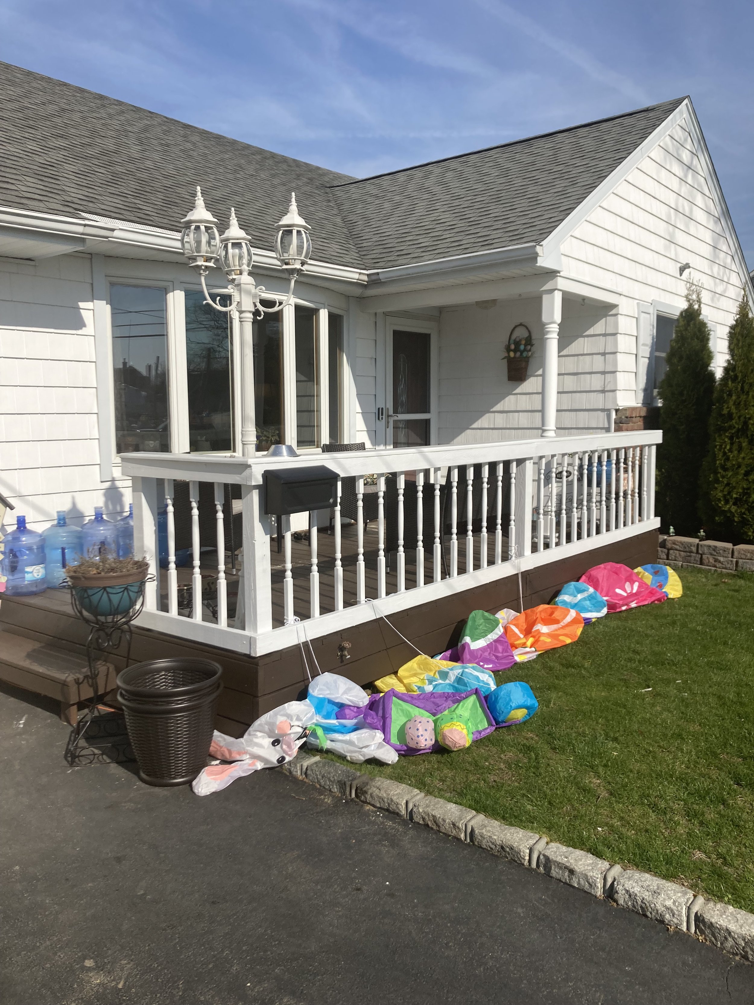White house with a porch and a chandelier, decorated with colorful lanterns and potted plants.