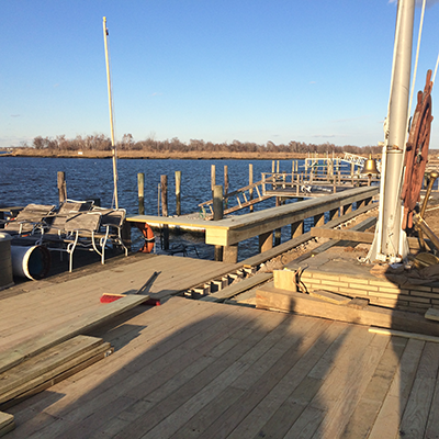 Newly constructed wooden dock extending into a body of water on a sunny day.