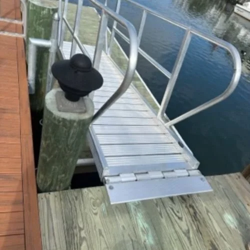 A small metal dock with a ramp leading into the water, featuring a black lamp on a green wooden post at the corner.