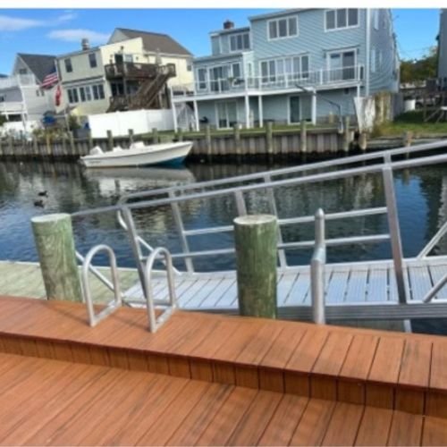 View of a canal with floating dock, boat, and houses in the background.