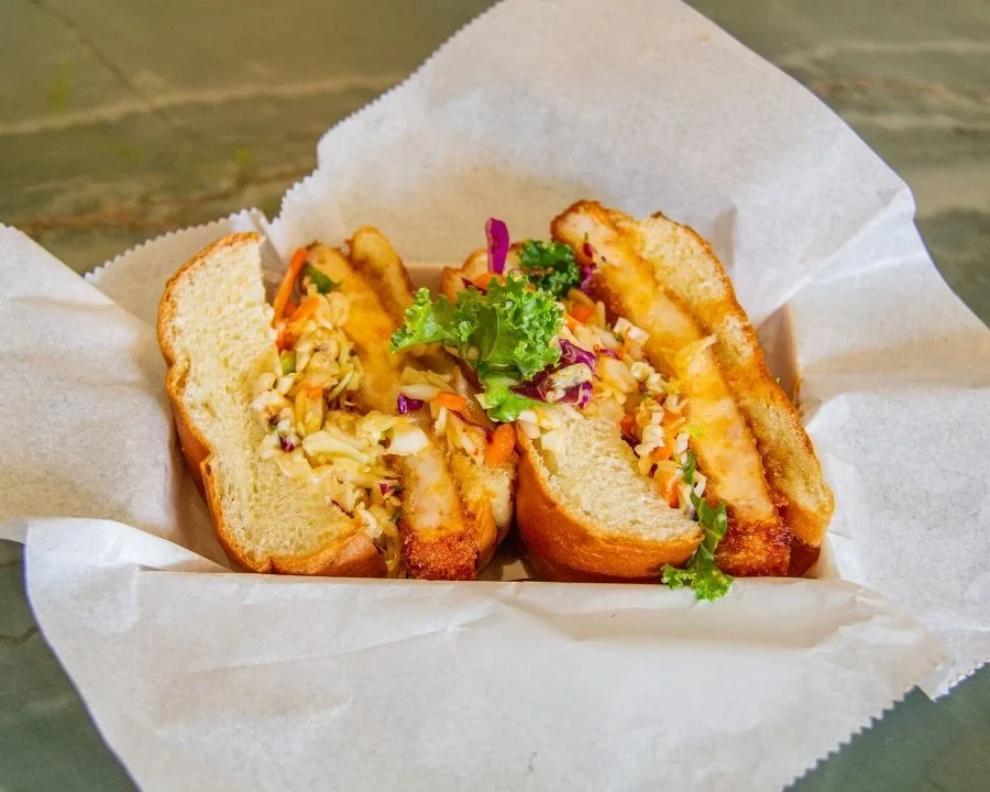 Two halves of RIKYŪ’s actual ebi-katsu shrimp sandwich with crisp golden filling and fresh coleslaw.