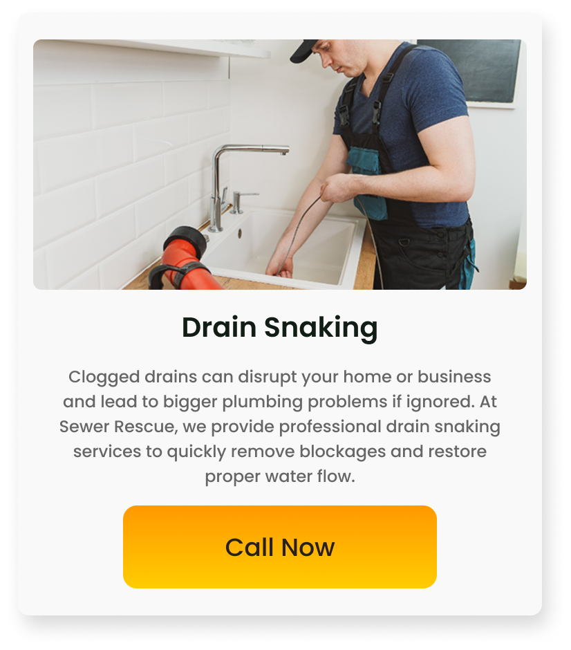 A technician snaking a clogged kitchen sink with a drain auger in a home kitchen.