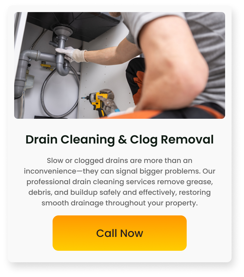 A plumber working under a kitchen sink using a drill for drain cleaning and clog removal.