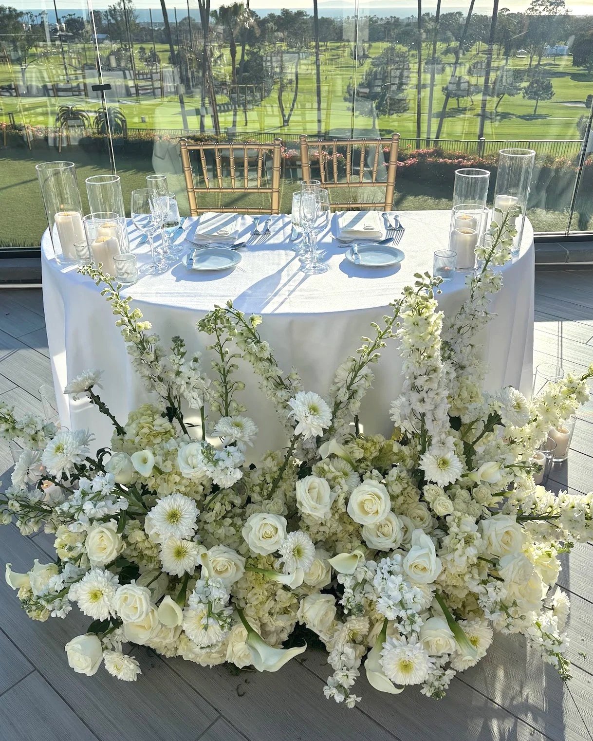 Sweetheart table, with large floral structure in fron. The floral structure is made with all white flowers.