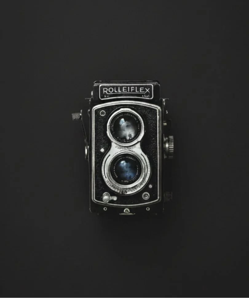 A vintage Rolleiflex twin-lens reflex camera on a black background.