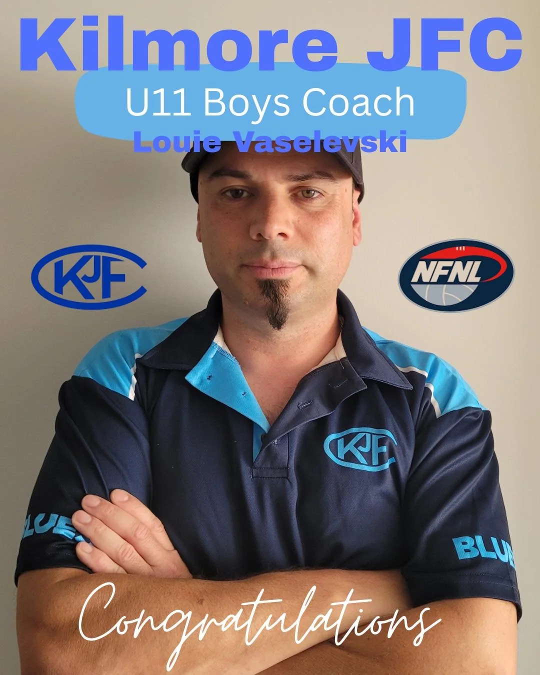 A man wearing a navy blue and light blue sports shirt with logos, standing with arms crossed, with text overlay indicating he is Louie Vaseleski, the U11 boys coach for Kilmore JFC.