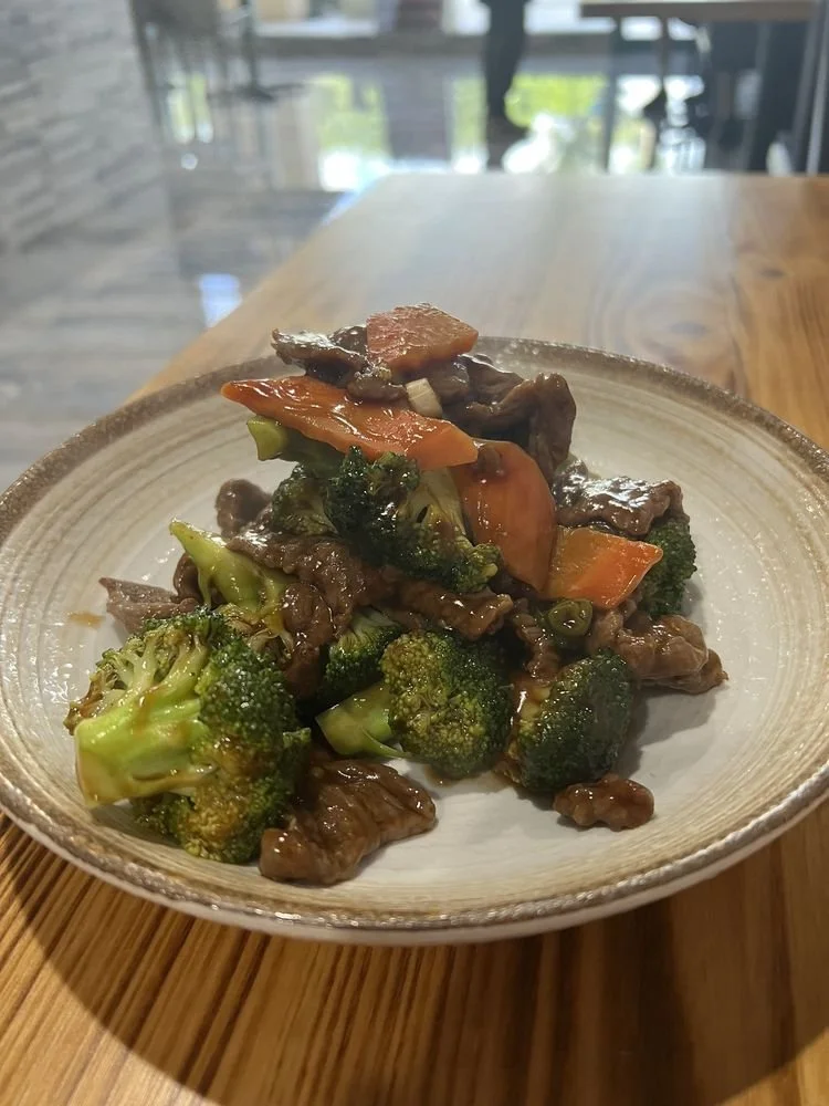 Stir-fried beef with broccoli and mixed vegetables on a ceramic plate.
