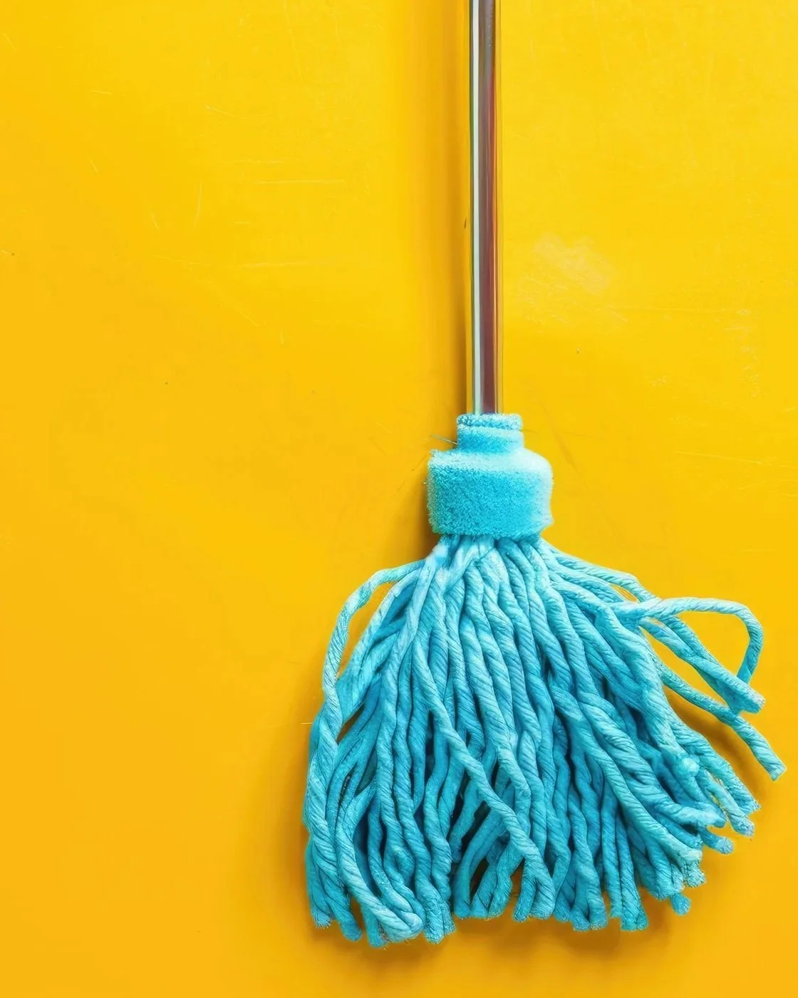 Blue microfiber mop with a metal handle on a yellow background.